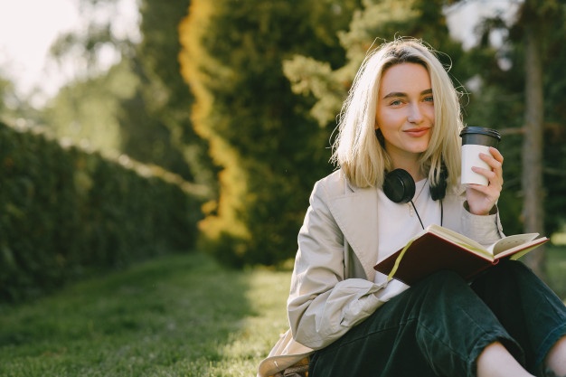 Blonde sitting on a grass with headphones